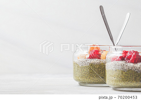Chia pudding with matcha tea and berries in glass jar, white background. Healthy food concept. Chia pudding with matcha tea and berries in glass jar, white background. Healthy food concept. 70200453