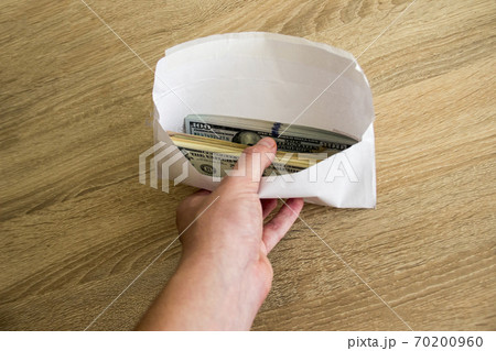 White envelope with money in a man's hand. Dollars are in a large envelope held by a man. 70200960