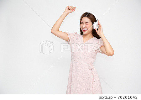 Young Asian woman listening music with headphones isolated on white background Young Asian woman listening music with headphones isolated on white background 70201045