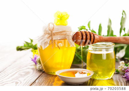 Honey pot and honey stick with summer flowers on rustic wooden table Honey pot and honey stick with summer flowers on rustic wooden table 70203588