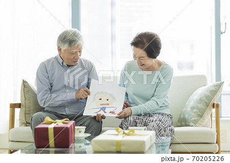 似顔絵を持って笑顔のシニア夫婦 70205226