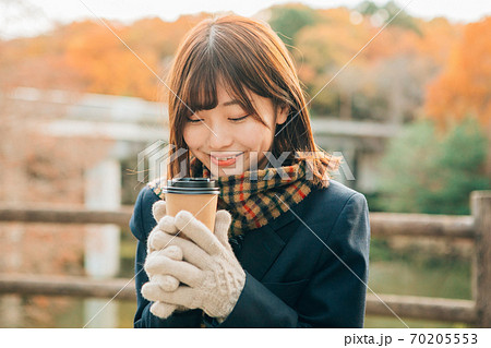 冬の屋外でホットドリンク コーヒー を飲む高校生の写真素材