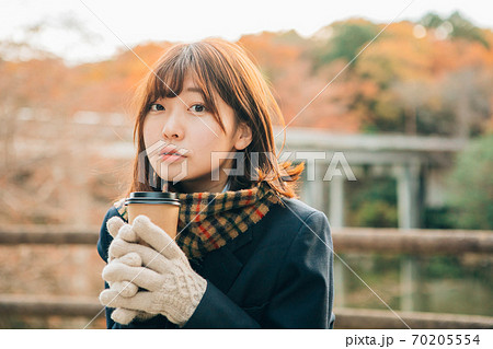 冬の屋外でホットドリンク コーヒー を飲む女子高生の写真素材