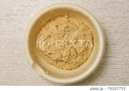 Mixed mixture of yeast dough ingredients, ready for lifting. The process of cooking in a light round large plastic bowl. Mixed mixture of yeast dough ingredients, ready for lifting. The process of cooking in a light round large plastic bowl. 70207752