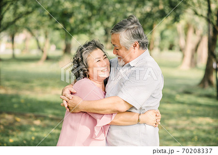 Happy senior Asian couple hugging outdoor in park Happy senior Asian couple hugging outdoor in park 70208337