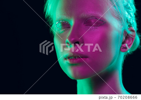Portrait of beautiful albino girl isolated on dark studio background in neon light Portrait of beautiful albino girl isolated on dark studio background in neon light 70208666