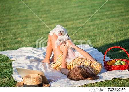 Little smiling girl playing with puppy in the park 70210282
