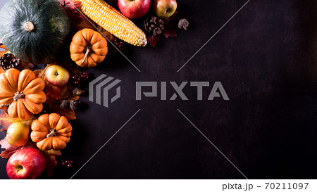 Thanksgiving background decor from dry leaves and pumpkin on dark stone  background. Flat lay, top view with copy space 70211097