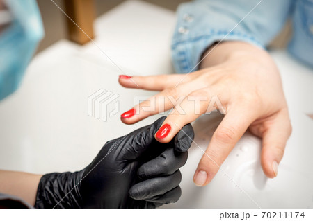 Young woman receives red nail polish 70211174
