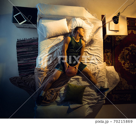 Top view of young professional basketball player sleeping at his bedroom in sportwear with ball Top view of young professional basketball player sleeping at his bedroom in sportwear with ball 70215869
