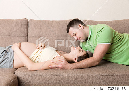 Loving pregnant couple hugs on bed in morning 70216138