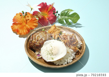 チキンナゲットやナポリタンも一緒に乗っている熱々のロコモコ丼とハイビスカスの造花 70216593