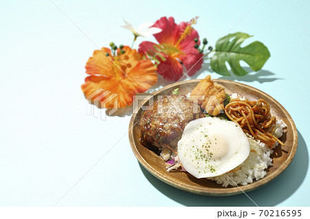 チキンナゲットやナポリタンも一緒に乗っている熱々のロコモコ丼とハイビスカスの造花 70216595