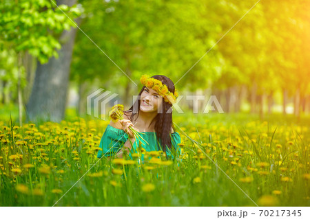 beautiful girl enjoys spring with a wreath of dandelions on her head beautiful girl enjoys spring with a wreath of dandelions on her head 70217345