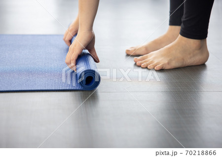 Close-up on Woman Folding Blue Yoga Mat on the Ground 70218866