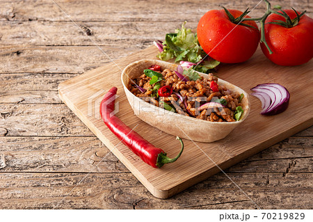 Mexican barquita taco with beef, chilli, tomato, onion and spices on wooden table Mexican barquita taco with beef, chilli, tomato, onion and spices on wooden table 70219829