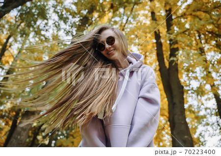 Young woman wearing pink hoodie and jeaans having fun in the park at sunny autumn day. Season and people concept. 70223400