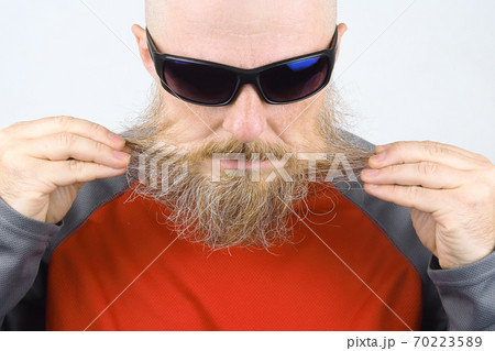 Portrait of a bald, bearded man wearing dark glasses on a light background 70223589