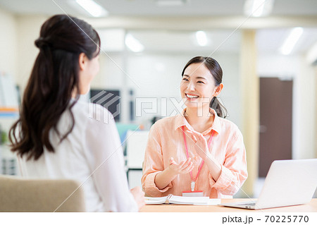 オフィスで若い女性の相談にのるカジュアルなビジネスウーマン オフィスで若い女性の相談にのるカジュアルなビジネスウーマン 70225770