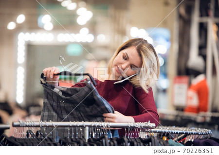 A blonde girl talking on a mobile phone, while shopping in a mal 70226351