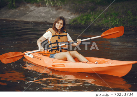 Woman paddling on a lake in a kayak Woman paddling on a lake in a kayak 70233734
