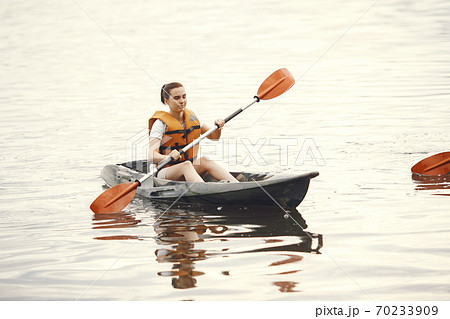 Woman paddling on a lake in a kayak Woman paddling on a lake in a kayak 70233909