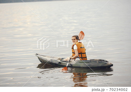 Woman paddling on a lake in a kayak 70234002