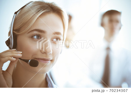 Call center and business people concept. Beautiful business woman with headphones consulting clients Call center and business people concept. Beautiful business woman with headphones consulting clients 70234307