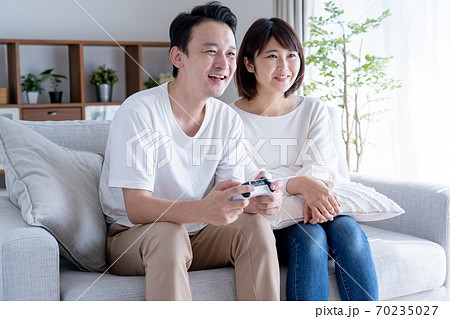 家でゲームをするアジア人カップルの写真素材
