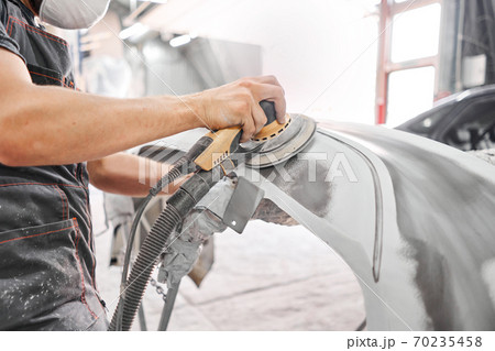 The mechanic works with a grinding tool. Sanding of car elements. Garage painting car service. Repairing car section after the accident. 70235458