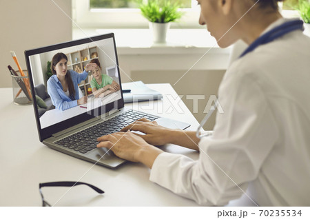 Doctor communicating with mother and son with high temperature and giving recommendations online on laptop 70235534