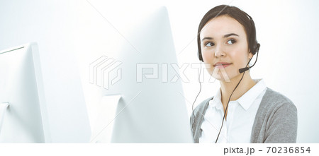 Call center. Casual dressed woman working in headset with diverse colleagues at office. Business concept Call center. Casual dressed woman working in headset with diverse colleagues at office. Business concept 70236854