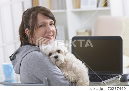 Hearing impaired woman with her dog at home office Hearing impaired woman with her dog at home office 70237449