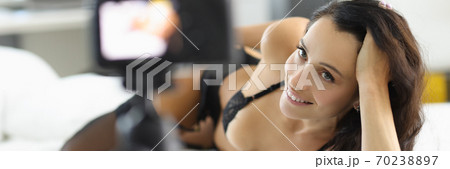 Woman in lingerie lies on bed and smiles. Woman in lingerie lies on bed and smiles. 70238897