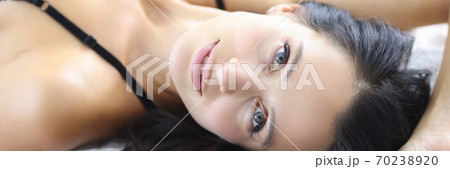 Portrait of a brunette woman lies on bed in a bra. 70238920
