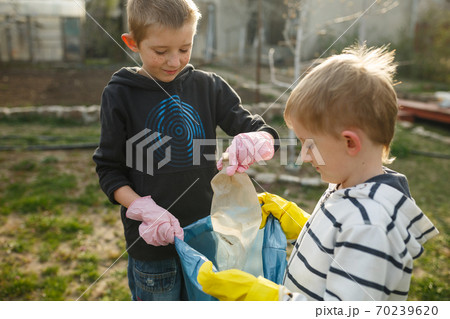 Two little boys in park collect plastic bottles 70239620