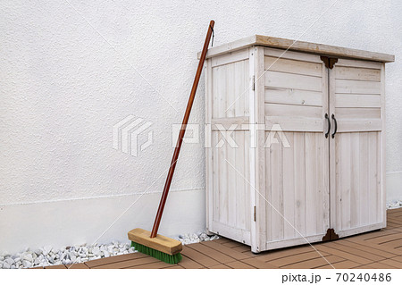 斜めから見た白の収納庫と立てかけられたデッキブラシの写真素材