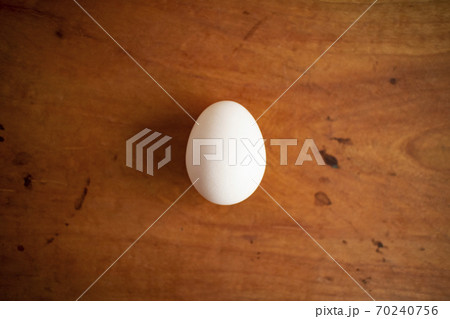 テーブルの上の白い新鮮な卵 a white fresh egg on a wooden table  70240756