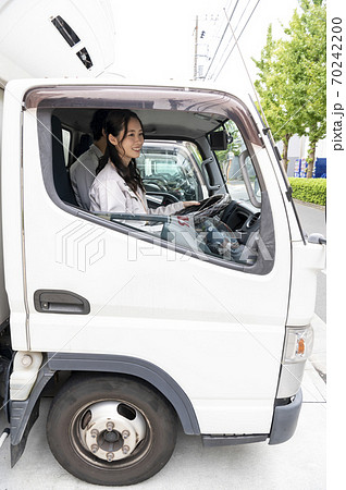 トラックを運転する若い女性ドライバーの写真素材
