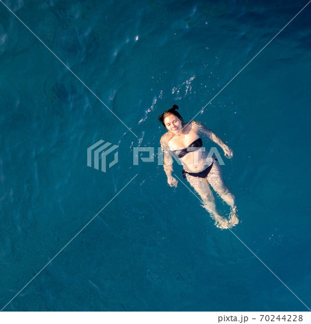aerial top view happy young woman in black swimsuit swims in the Red Sea, Egypt, Sharm el Sheikh 70244228