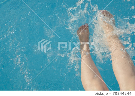 cropped young european woman kicks in the pool splashes water. Concept, carefree, summer, vacation cropped young european woman kicks in the pool splashes water. Concept, carefree, summer, vacation 70244244