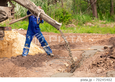 Construction worker laying cement or concrete into the foundation formwork Construction worker laying cement or concrete into the foundation formwork 70245402