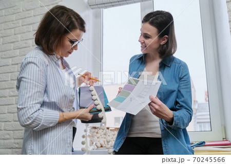 Women designers choosing fabrics and accessories for curtains Women designers choosing fabrics and accessories for curtains 70245566