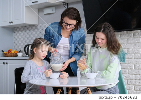 Children with mother eating at home in kitchen Children with mother eating at home in kitchen 70245633