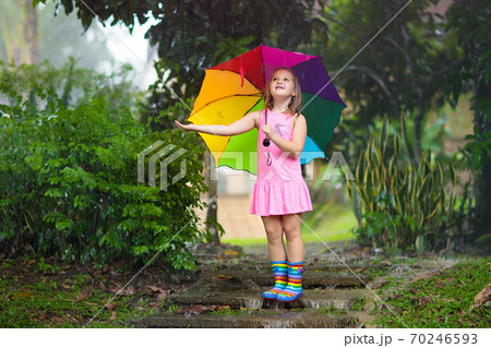Kid with umbrella playing in summer rain. Kid with umbrella playing in summer rain. 70246593