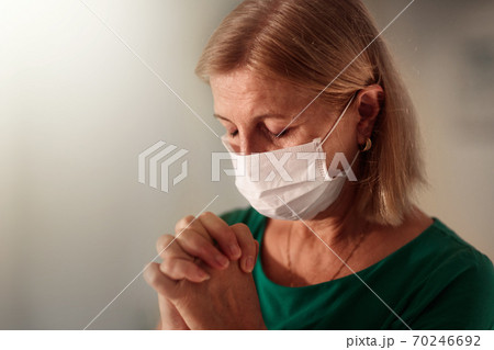 Woman in face mask praying for sick patient Woman in face mask praying for sick patient 70246692