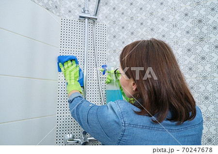 Woman cleaning and polishing shower, glass, faucet, tiled wall Woman cleaning and polishing shower, glass, faucet, tiled wall 70247678