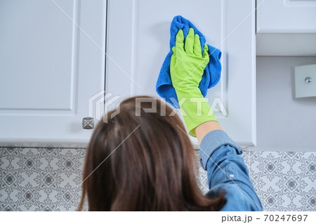 Woman in gloves with rag cleaning, polishing furniture on kitchen Woman in gloves with rag cleaning, polishing furniture on kitchen 70247697