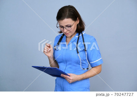 Portrait of mature nurse woman holding clipboard 70247727