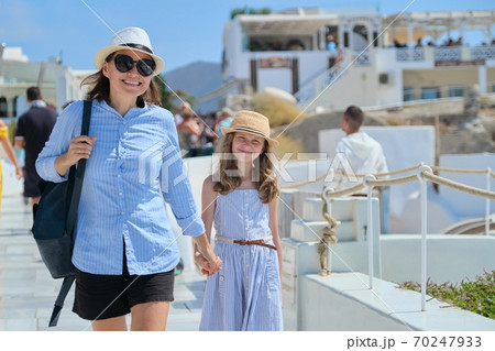 Mother walking with daughter child in famous tourist village Oia Santorini 70247933